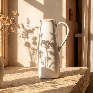 The Watermill Jug in a soft white glaze styled with fresh stems on a relaxed dining table