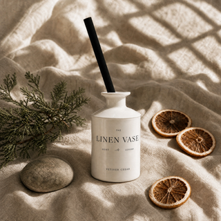 Vetiver Cedar Signature Reed Diffuser on ecru linen with dried citrus, cedar sprig and river stone