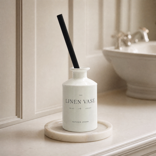 Vetiver Cedar Signature Reed Diffuser on Marble Candle Plate Holder in a traditional bathroom